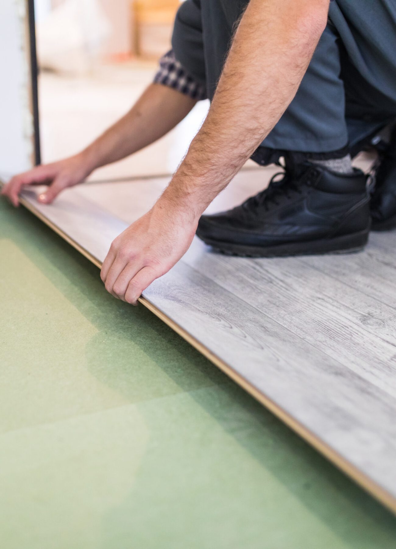 Young worker laying a floor with bright laminated flooring boards